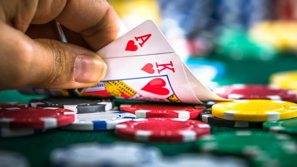 Gambling Hand Holding Poker Cards and Money Coins Chips.