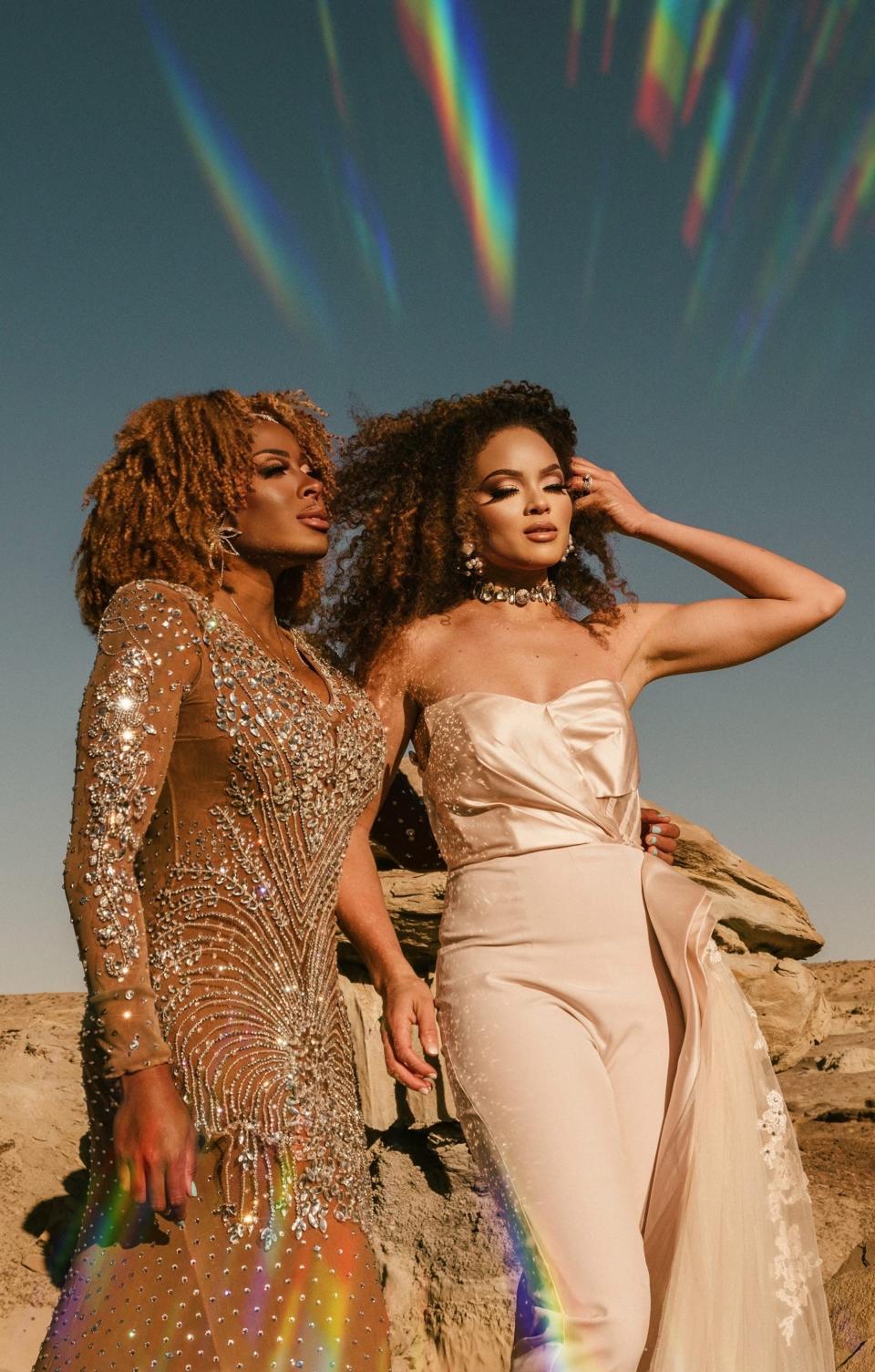 Two brides pose in their wedding attire in a desert.