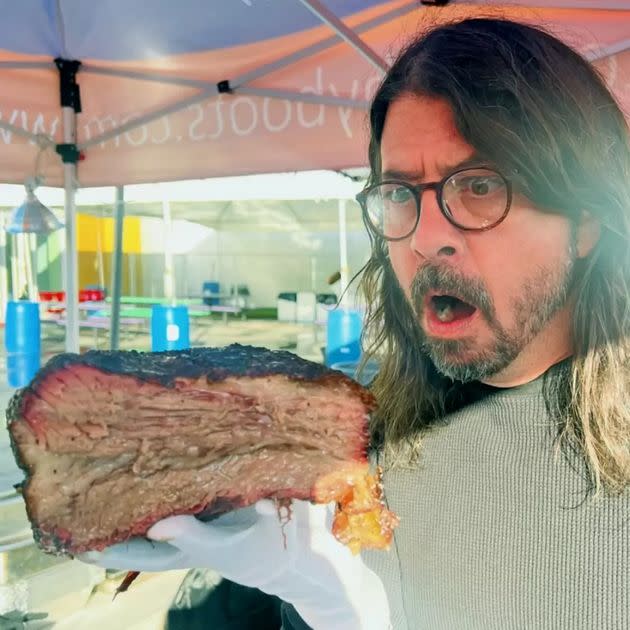 Grohl admires the barbecue meat he prepared for hundreds in need.