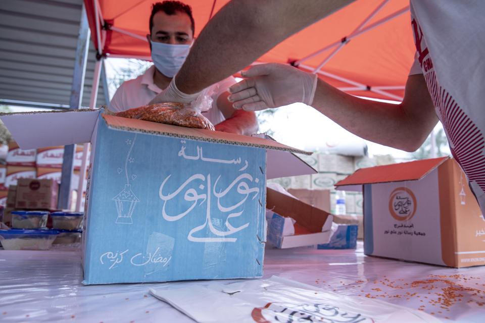 Non-governmental organization Resala Nour Ala Nour workers prepare cartons filled with food to distribute to people who have been greatly affected by the coronavirus outbreak, in Cairo, Egypt, Thursday, April 9, 2020. (AP Photo/Nariman El-Mofty)