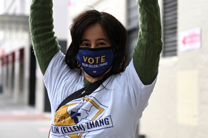 Miranda wears a campaign-branded mask as she holds a poster near a polling station on D.C.'s primary election day in Washington