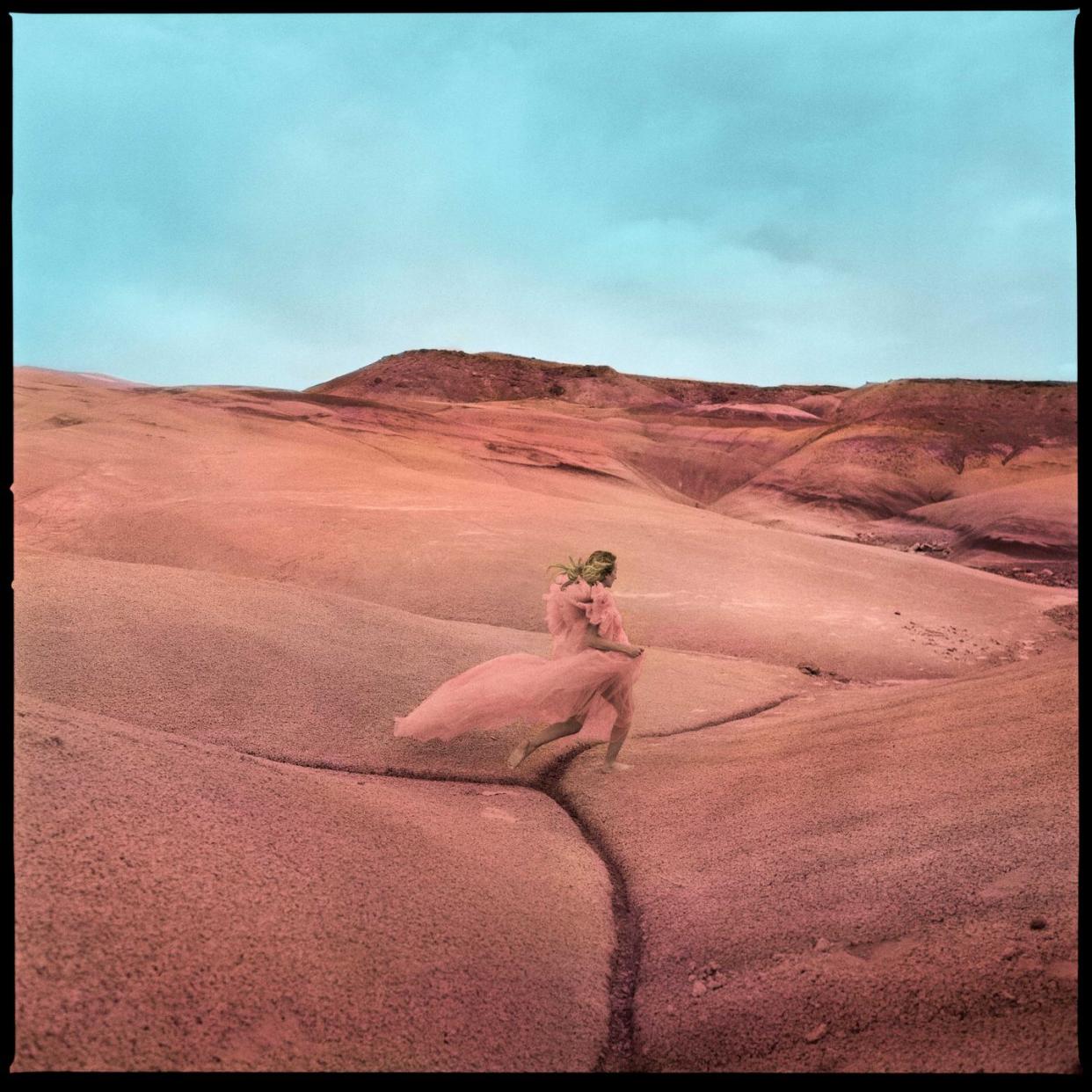 margo price runs in a pink dress across red rocks