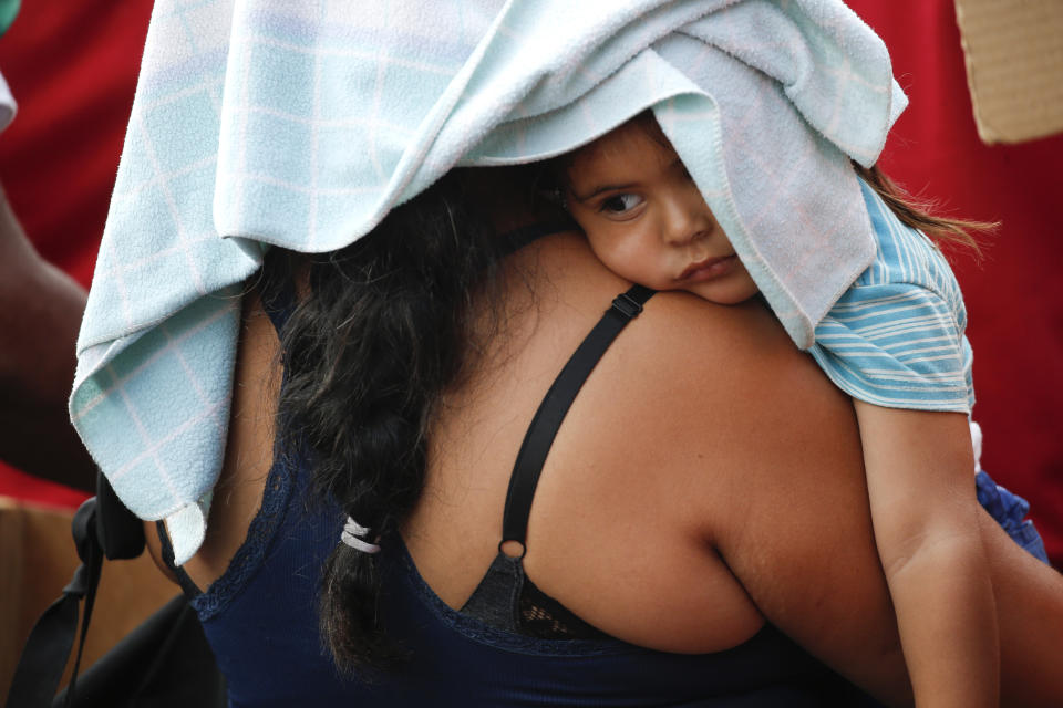 In this March 23, 2019 photo, a government supporter cradles a child as she listens to Venezuela's President Nicolas Maduro during an anti-imperialist rally in Caracas, Venezuela. Political turmoil in Venezuela increased when President Nicolas Maduro's 2018 re-election was deemed illegitimate by several governments and Assembly President Juan Guido declared himself interim president of the country. (AP Photo/Natacha Pisarenko)