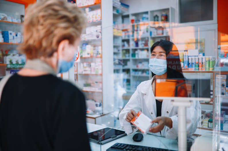 A person speaking with a pharmacist and getting medicine.