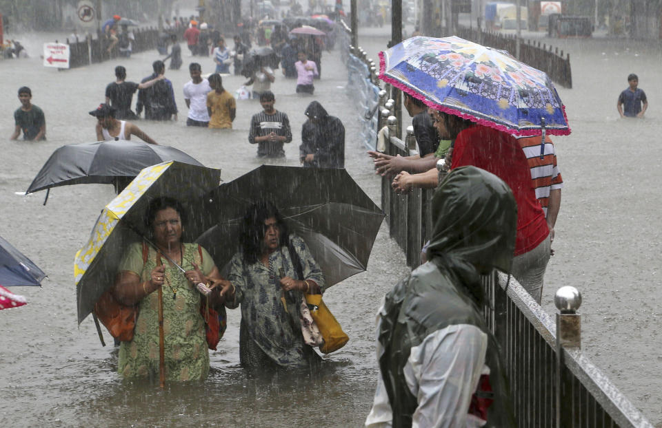 People navigate their way through a street flooded by torrential rains in Mumbai, India, on Sept. 4, 2019. (AP Photo/Rajanish Kakade)