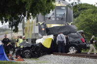 FILE - In this Aug 25, 2019 file photo, Broward Sheriff's Deputies and Pompano Beach Fire Rescue work the scene of a fatal accident on North Dixie Highway in Pompano Beach, Fla. The Florida higher-speed passenger train service tied to Richard Branson’s Virgin Group has the worst per-mile death rate in the U.S. The first death involving a Brightline train happened in July 2017 during test runs. An Associated Press analysis of Federal Railroad Administration data shows that since then, 40 more have been killed. That amounts to a rate of more than one a month and about one for every 29,000 miles (47,000 kilometers) the trains have traveled since the first death. (Joe Cavaretta/South Florida Sun-Sentinel via AP)