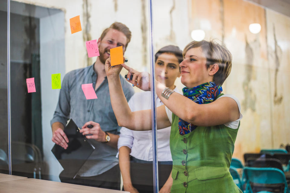 A person sticks notes on a glass wall