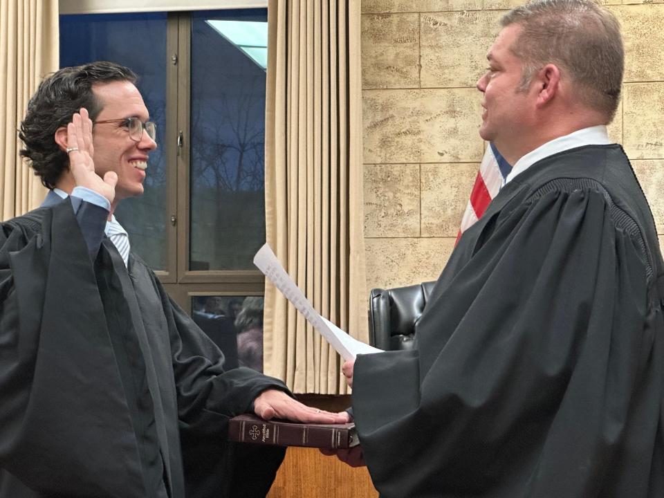 Mark Dunn (left) places his hand on his grandfather's bible while being sworn in as Great Fall's second Municipal Court Judge on Tuesday