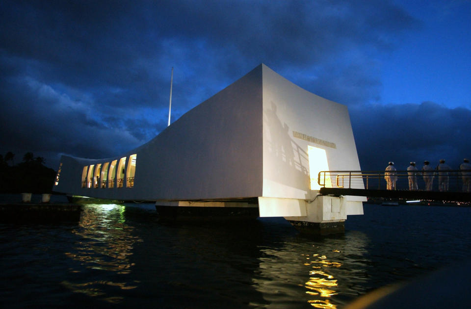 Sailors stand outside the USS Arizona Memorial at daybreak in Pearl Harbor, Hawaii, December 7, 2004. At the 63rd Annual Memorial Service which took place at 7:55 am Tuesday morning, the exact time the Japanese attack began in 1941, a moment of silence was observed throughout the pacific naval base, as the Hawaii Air national guard F-15's flew overhead in the missing man formation. The service included prayers and a rifle salute, along with 40 wreaths presented by Pearl Harbor survivors, military, diplomatic and government officials. REUTERS/Lucy Pemoni  LP/MR