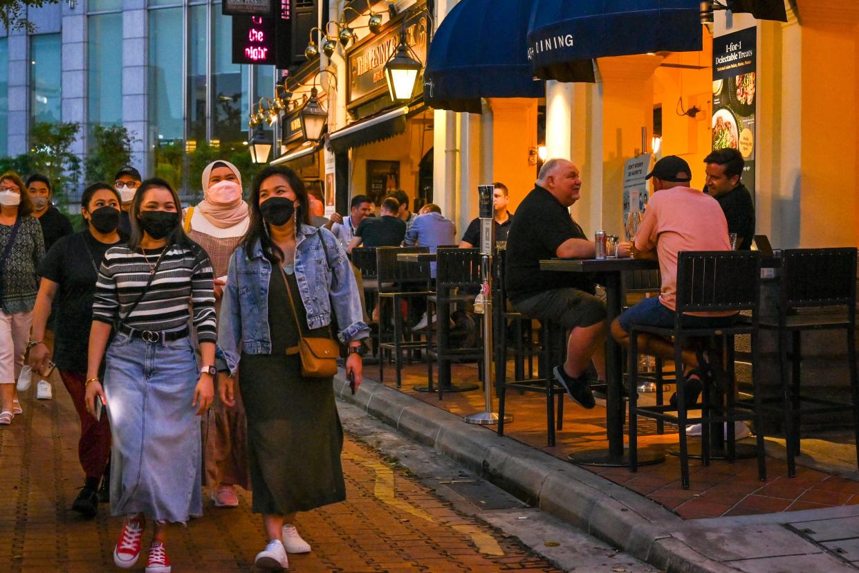 In this photograph taken on February 18, 2022, patrons enjoy their drinks at bars along Boat Quay in Singapore. - Rivals Singapore and Hong Kong have become pandemic polar opposites, the former opting to live with the coronavirus and reopen to the world while the latter doubles down on zero-Covid and its international isolation. - To go with AFP story Health-virus-Hong Kong-China-Singapore, FOCUS by Holmes Chan with Catherine Lai in Singapore (Photo by Roslan RAHMAN / AFP) / To go with AFP story Health-virus-Hong Kong-China-Singapore, FOCUS by Holmes Chan with Catherine Lai in Singapore (Photo by ROSLAN RAHMAN/AFP via Getty Images)