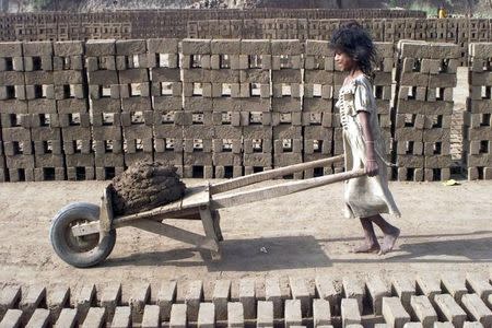 A girl pushes a cart carrying cement at a brick factory in Jammu April 13, 2003. REUTERS/Amit Gupta/Files