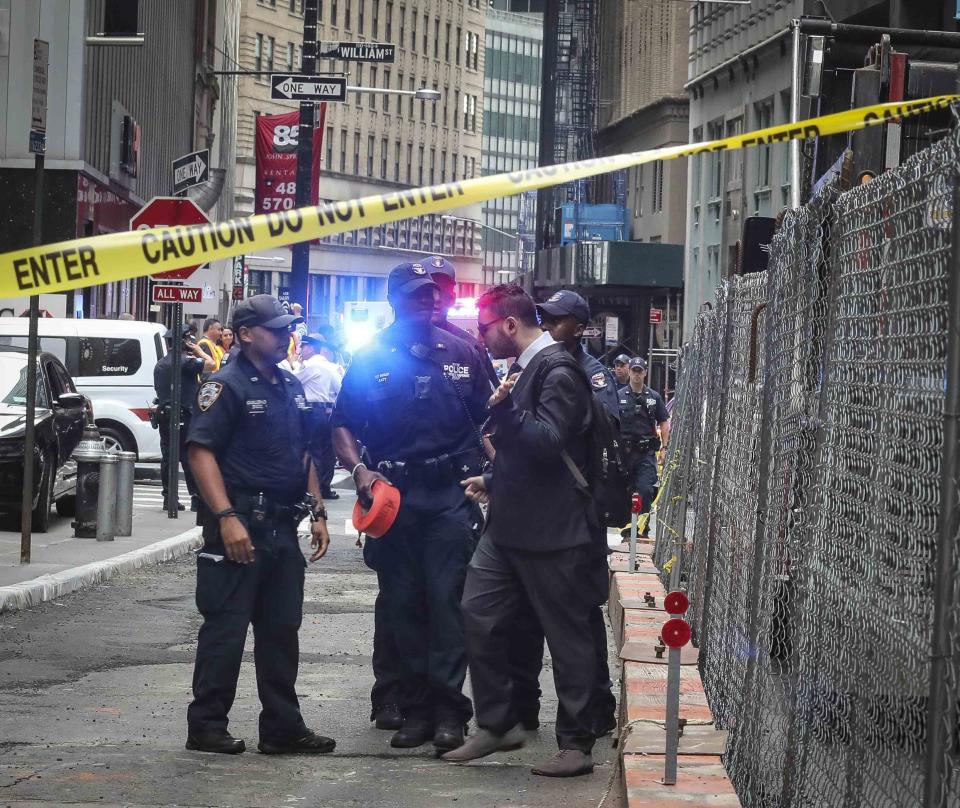 NYPD officers block an individual attempting to bypass a taped-off zone, as police seal off area in the financial district around the the Fulton Street subway hub to investigate a suspicious item, Friday Aug. 16, 2019, in New York. Two abandoned objects that appeared to be pressure cookers prompted an evacuation of a major lower Manhattan subway station during the morning commute Friday before police determined they were not explosives, and authorities were investigating whether they were deliberately positioned to spark fear. (AP Photo/Bebeto Matthews)