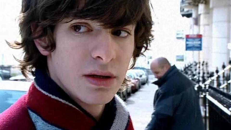 Andrew Garfield stands on a street