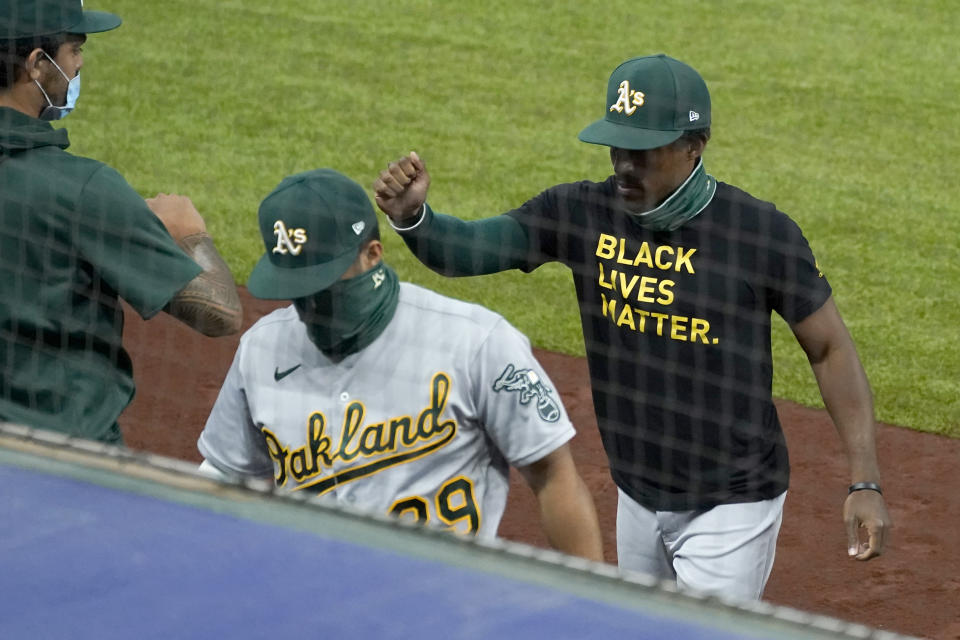 Oakland Athletics' Tony Kemp, right, wears a Black Lives Matter shirt as he greets teammates before the start a baseball game against the Texas Rangers in Arlington, Texas, Wednesday Aug. 26, 2020. (AP Photo/Tony Gutierrez)