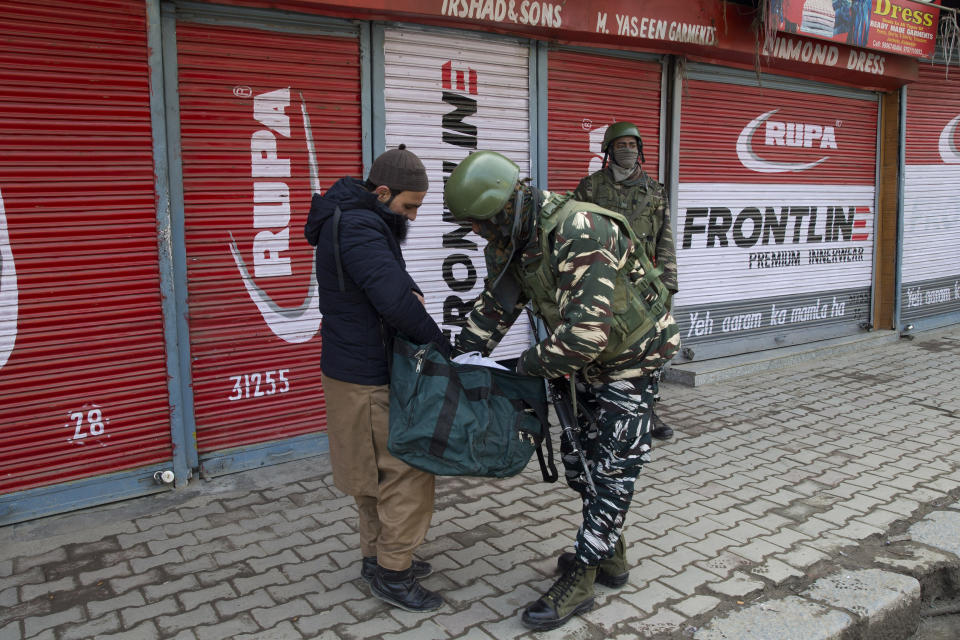 An Indian paramilitary soldier checks the bag of a Kashmiri man during a strike in Srinagar, Indian controlled Kashmir, Sunday, Feb. 3, 2019. India's prime minster is in disputed Kashmir for a daylong visit Sunday to review development work as separatists fighting Indian rule called for a shutdown in the Himalayan region. (AP Photo/Dar Yasin)
