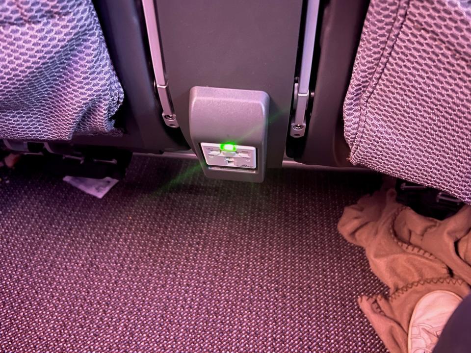 A view of the power outlet below the seat in front.