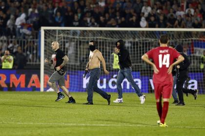 Ivan Bogdanov, left, jailed over a disruption of an Euro 2012 qualifier in Genoa, Italy in 2010, and others invade the pitch during the Euro 2016 Group I qualifying match between Serbia and Albania at the Partizan stadium in Belgrade, Serbia, Tuesday, Oct. 14, 2014. The European Championship qualifier between Serbia and Albania was suspended on Tuesday after pitch skirmishes involving players and fans over an Albanian flag that was flown above the stadium by a drone. (AP Photo/Marko Drobnjakovic)