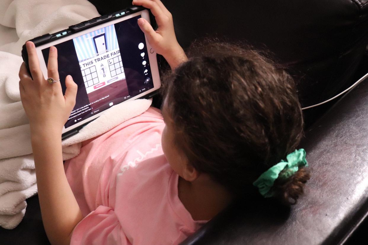 Girl plays and watches TikToks on iPad.