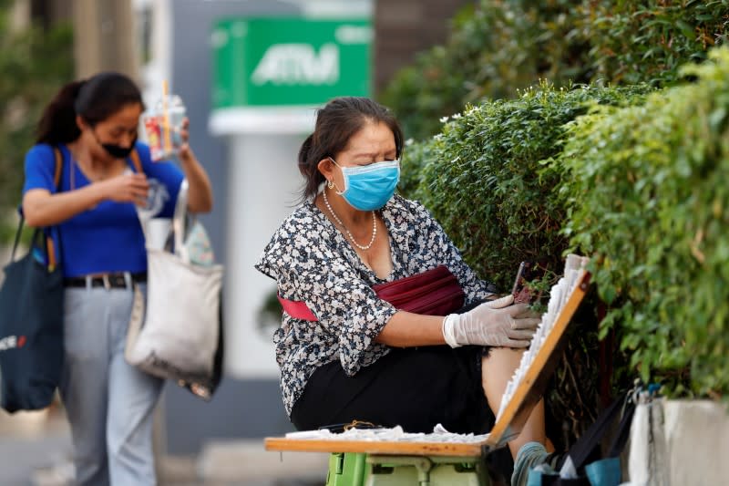 A woman sells lottery tickets on a street site as government postponed the April 1 lottery draw to May 2 due to coronavirus disease (COVID-19) outbreak, in Bangkok