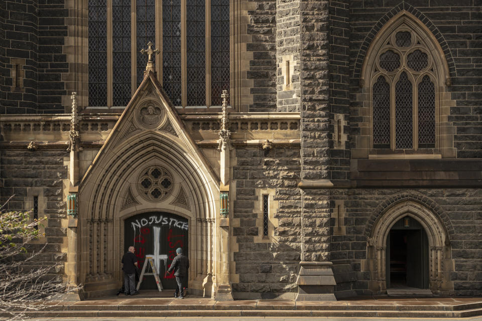 Workers cover graffiti at St Patrick's Cathedral in Melbourne, Australia, Wednesday, April 8, 2020. 