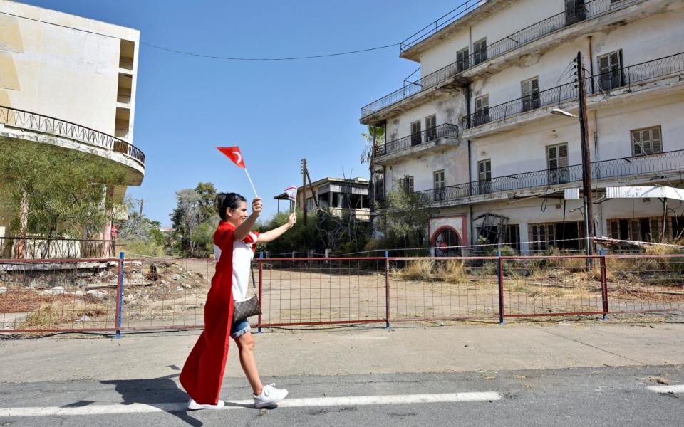 A woman holding Turkish and Turkish Cypriot flags inside the abandoned resort of Varosha  - Reuters