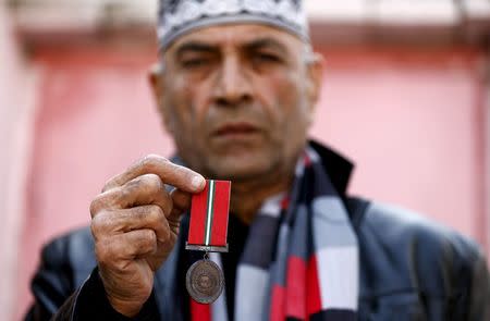 Aurangzeb Khan shows a medal for bravery awarded posthumously to his son Hassan Zeb at their home in Peshawar, Pakistan December 11, 2015. REUTERS/Caren Firouz