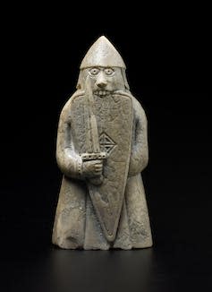 A chess piece depicting a berserker biting his shield.