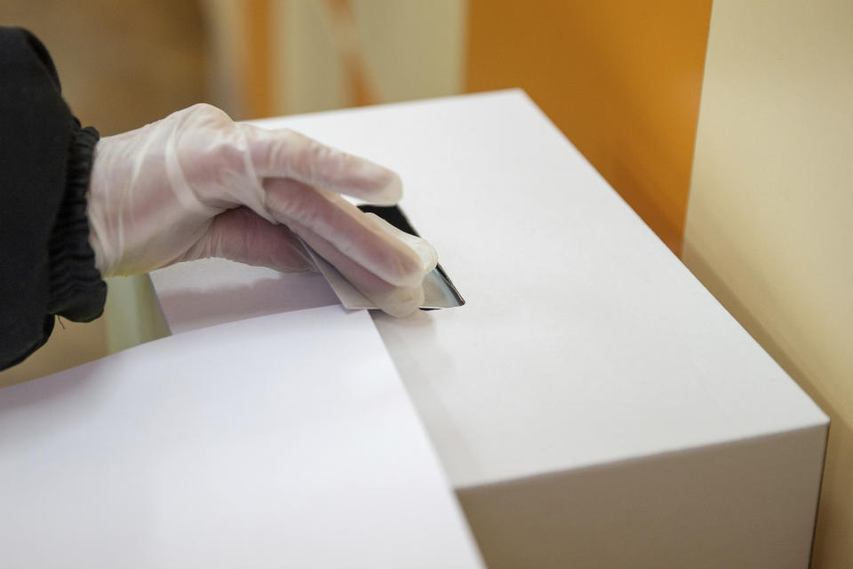 A woman casts her ballot during parliamentary elections in the town of during the parliamentary elections in the town of Bankya, Bulgaria, Sunday, April 4, 2021. Bulgarians are heading to the polls on Sunday to cast ballots for a new parliament after months of anti-government protests and amid a surge of coronavirus infections. (AP Photo/Visar Kryeziu)