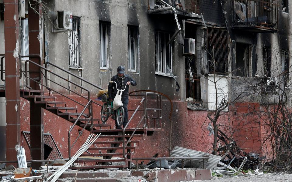 A man walks downstairs outside a residential building damaged during Ukraine-Russia conflict in the southern port city of Mariupol, Ukraine - Alexander Ermochenko/Reuters