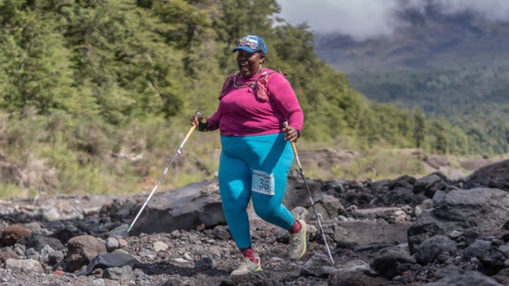 Mirna running across technical trail with a pink shirt and blue pants