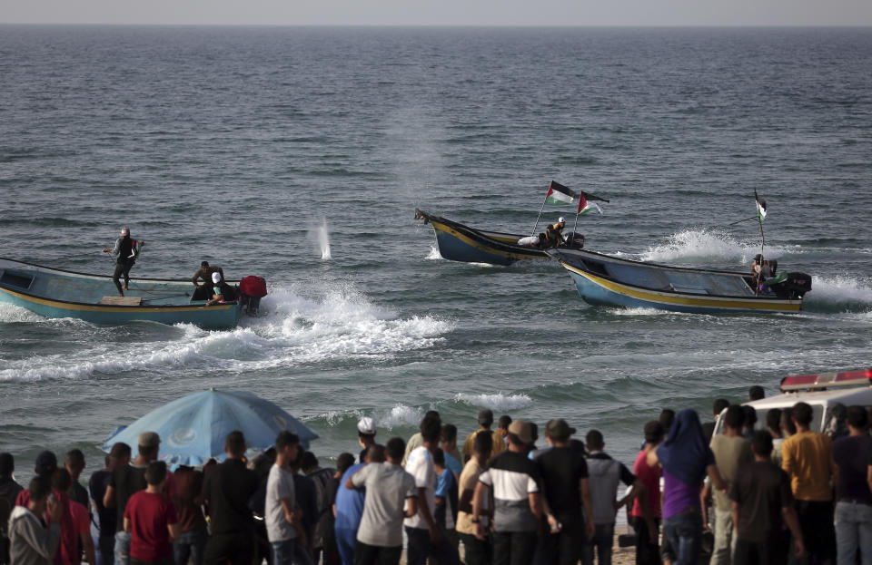 Palestinian protesters watch fishing boats flee from the fire shooting by Israeli troops during a protest on the beach at the border with Israel near Beit Lahiya, northern Gaza Strip, Monday, Oct. 22, 2018. (AP Photo/Khalil Hamra)