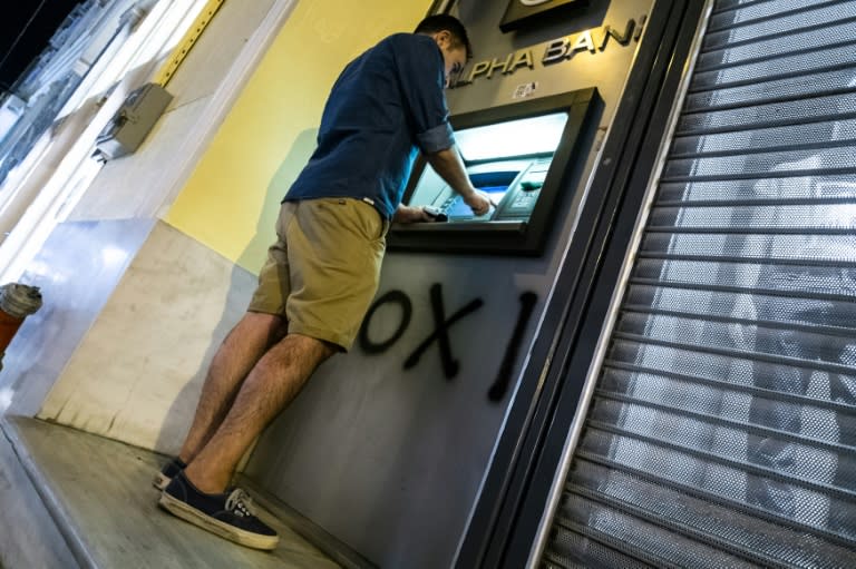 A man withdraws money from an ATM in downtown Athens on July 5, 2015