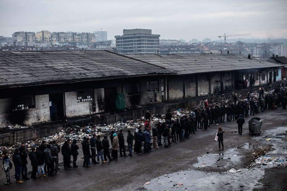 <p>Refugees and migrants queue for food provided by volunteers at an abandoned storage complex near the Central train station inBelgrade, Serbia, Feb. 2017. (Manu Brabo/MeMo) </p>