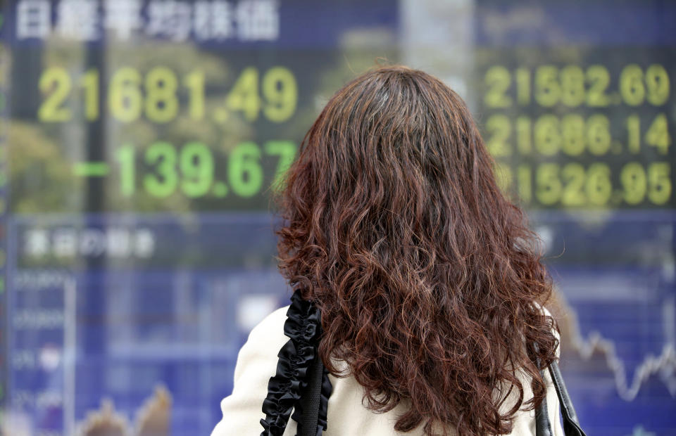 A woman looks at an electronic stock board of a securities firm in Tokyo, Tuesday, Nov. 20, 2018. Asian stocks slid Tuesday after tech losses dragged down Wall Street and Nissan's chairman was arrested on charges of financial misconduct.(AP Photo/Koji Sasahara)