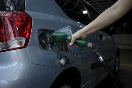 A worker pumps gas into a vehicle at a gas station, which belongs to Venezuela's state oil company PDVSA, in Caracas, February 13, 2016. REUTERS/Marco Bello