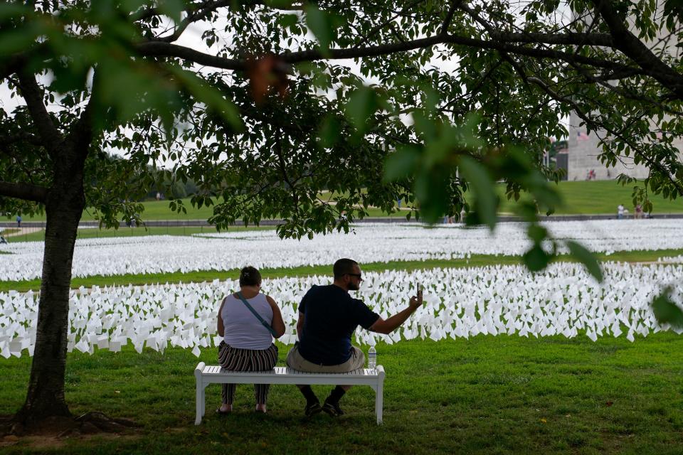 People visit artist Suzanne Brennan Firstenberg's "In America: Remember," a temporary art installation made up of white flags to commemorate Americans who have died of COVID-19, on the National Mall in Washington, Tuesday, Sept. 21, 2021. 