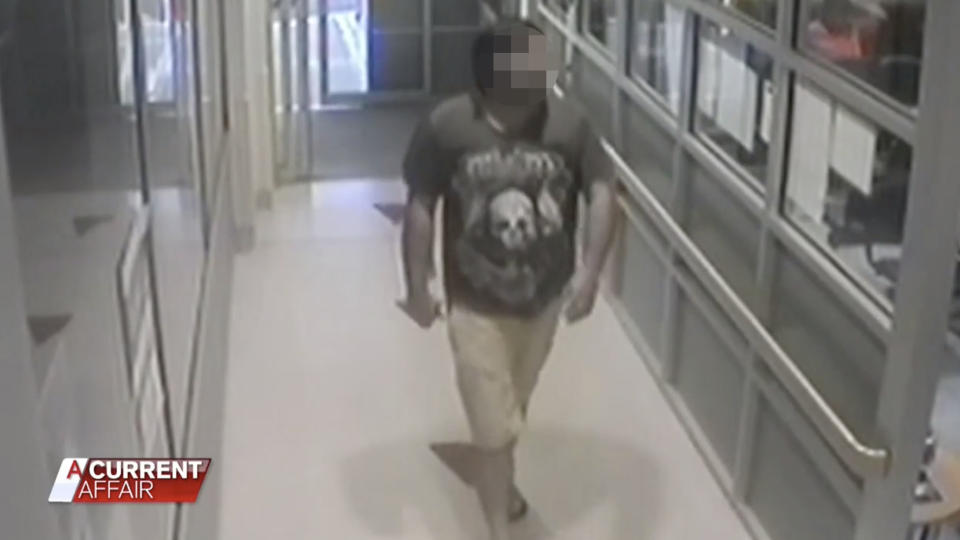 The man in shorts and t-shirt walks into the hospital holding a knife.