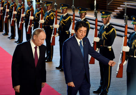 Russian President Vladimir Putin (L) is escorted by Japanese Prime Minister Shinzo Abe as they review an honor guard before their working lunch at Abe's official residence in Tokyo, Japan, December 16, 2016. REUTERS/Frank Robichon/Pool