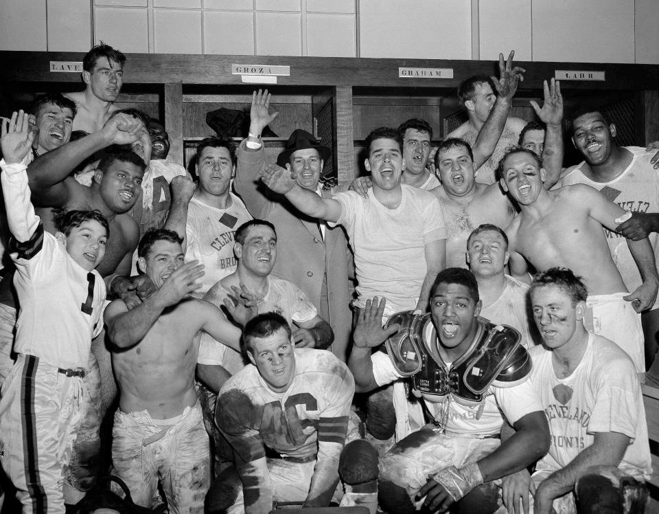 Browns players cheer in their dressing room after their 56-10 victory over the Detroit Lions to win the NFL title, Dec. 26, 1954 in Cleveland. Coach Paul Brown is at center background wearing a hat. Quarterback Otto Graham stands immediately to the right of Brown.