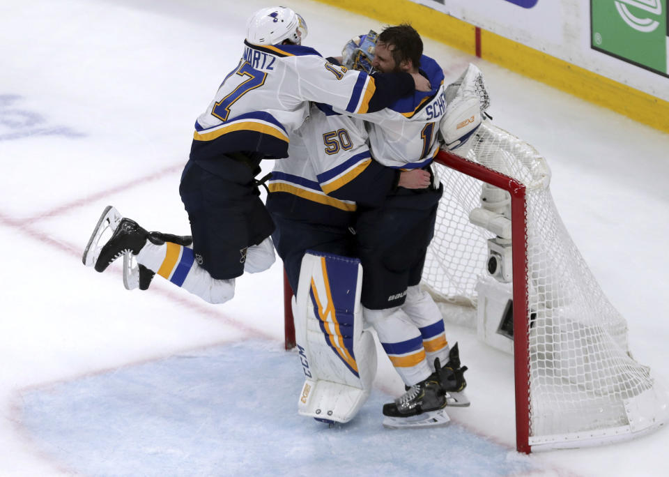 St. Louis Blues' Jaden Schwartz, left, and Brayden Schenn, right, mob goaltender Jordan Binnington, to celebrate their win over the Boston Bruins in Game 7 of the NHL hockey Stanley Cup Final, Wednesday, June 12, 2019, in Boston. (AP Photo/Charles Krupa)