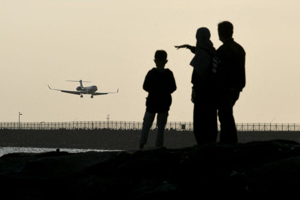People watch a plane landing at I Gusti Ngurah Rai International Airport on Indonesia's resort island of Bali on June 1, 2023. Indonesia is one of many countries that require visas for American tourists.