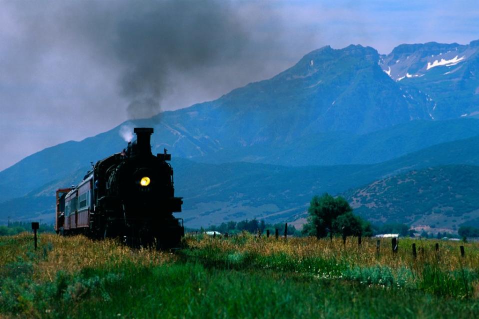 A railroad steam locomotive passes through the rustic valley of Herber City via Getty Images/<br>James L. Amos