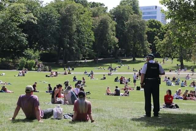 A PSNI officer monitors people enjoying the warm weather at the Botanic Gardens in Belfast (Niall Carson/PA)