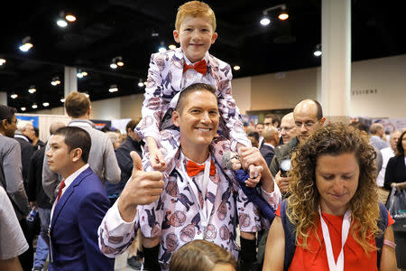 Ray Renk holds his 10-year-old son Benjamin as they wear matching custom-made suits printed with a caricature of Berkshire Hathaway Chief Executive Warren Buffett at the annual shareholder meeting in Omaha, Nebraska, U.S., May 4, 2019. REUTERS/Scott Morgan