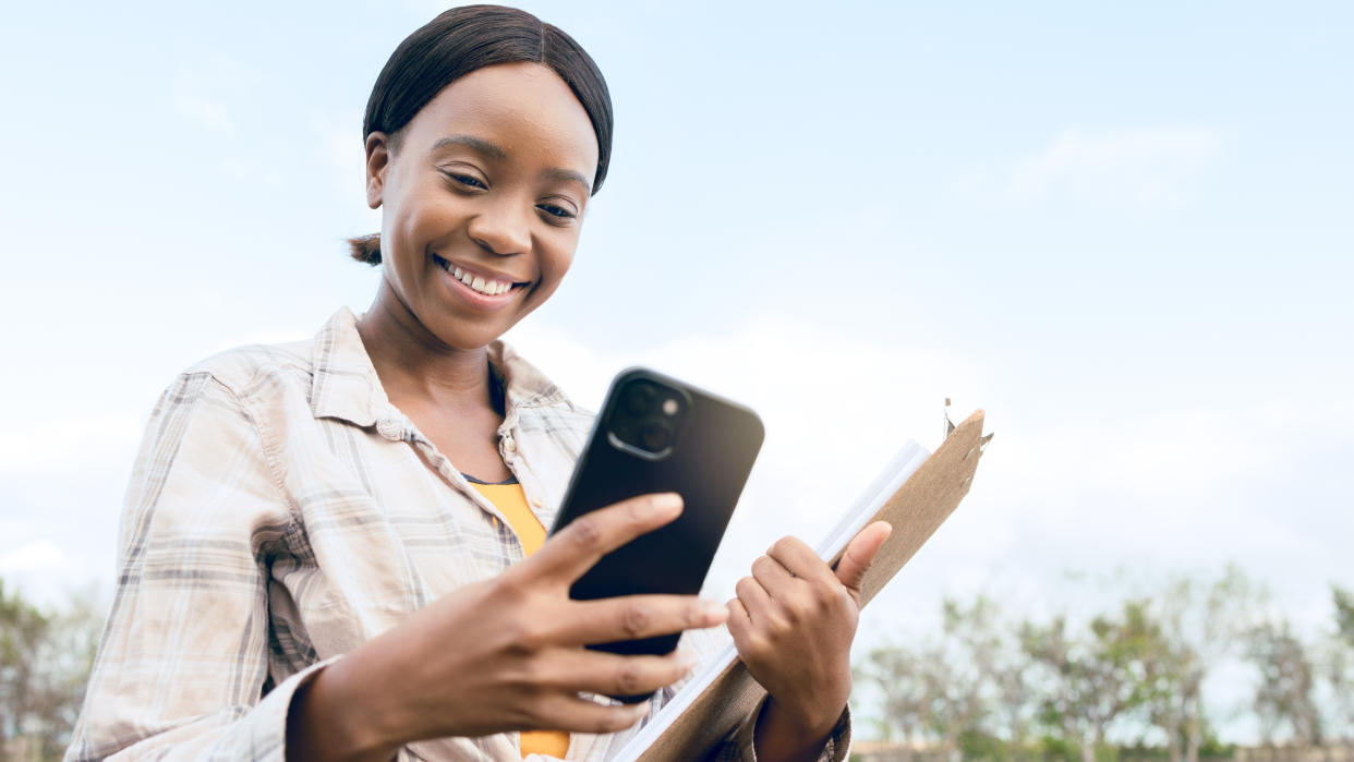  Woman holding iPhone and clipboard in a field 