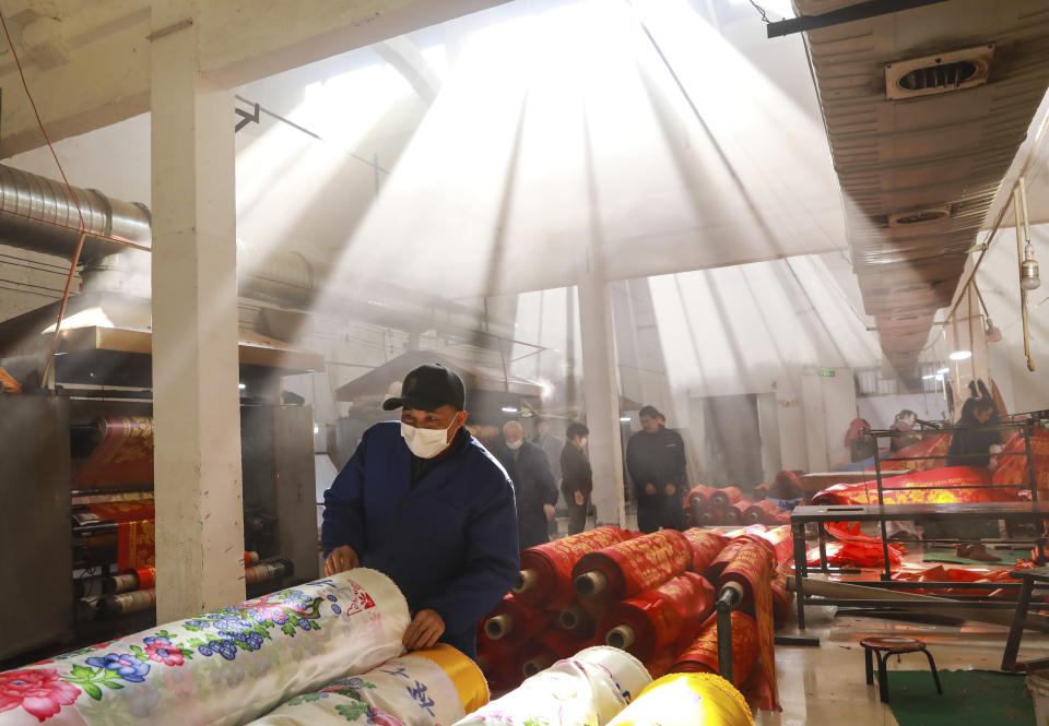 A worker looks at rolls of fabric in a weaving factory in Hangzhou in eastern China's Zhejiang Province, Friday, Jan. 6, 2023. Forecasters say the abrupt decision by President Xi Jinping's government to end controls that shut down factories and kept millions of people at home will move up the timeline for economic recovery, but might disrupt activity this year as businesses scramble to adapt. (Chinatopix via AP)