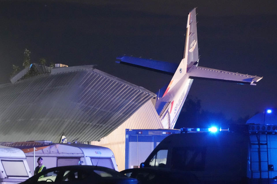 The tail of a Cessna 208 plane sticks out of a hangar after it crashed there in bad weather killing several people and injuring others, at a sky-diving center in Chrcynno, central Poland, on Monday, July 17, 2023. (AP Photo/Czarek Sokolowski)