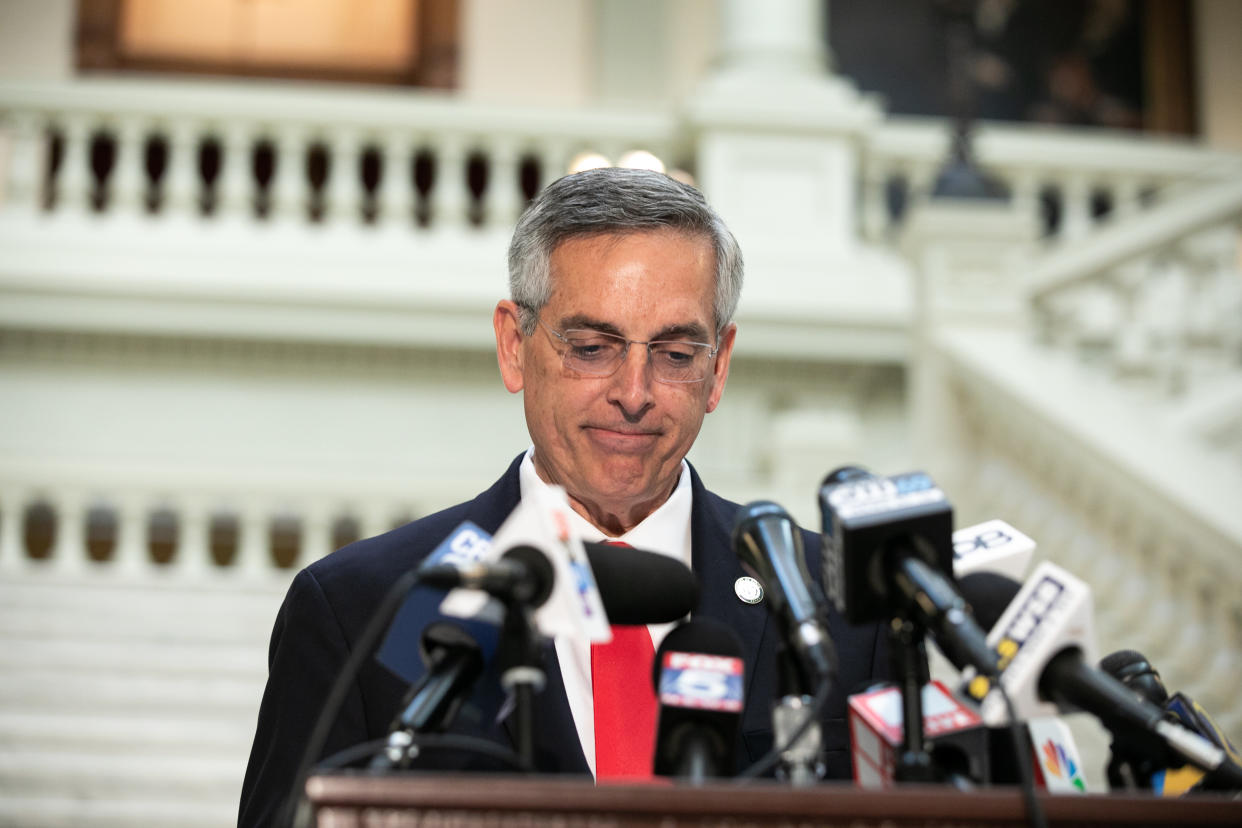 Georgia Secretary of State Brad Raffensperger stands in front of multiple microphones at a press conference.