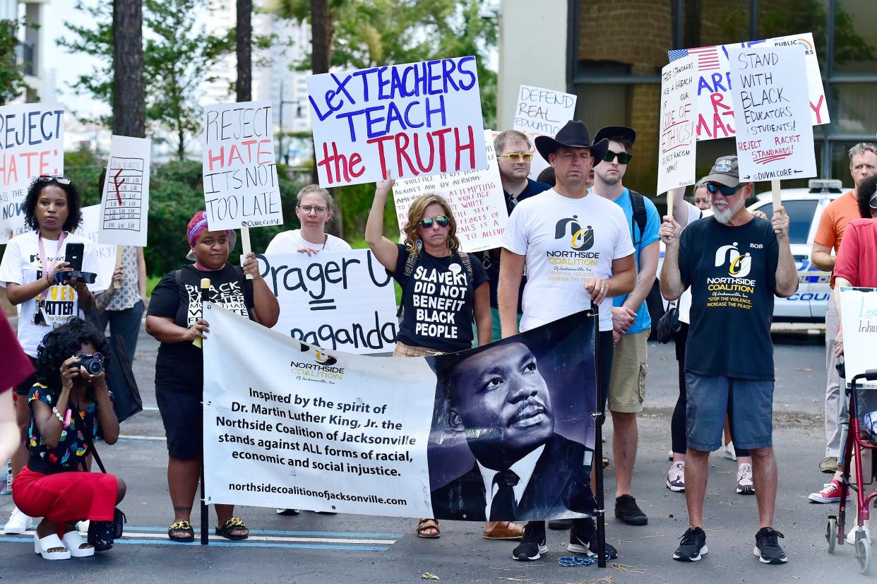 A group of protesters rally outside the Duval County School Board's headquarters Tuesday to oppose the new state-mandated Black history teaching standards, which critics fault as whitewashing that talks about slaves gaining job skills as a result of slavery.