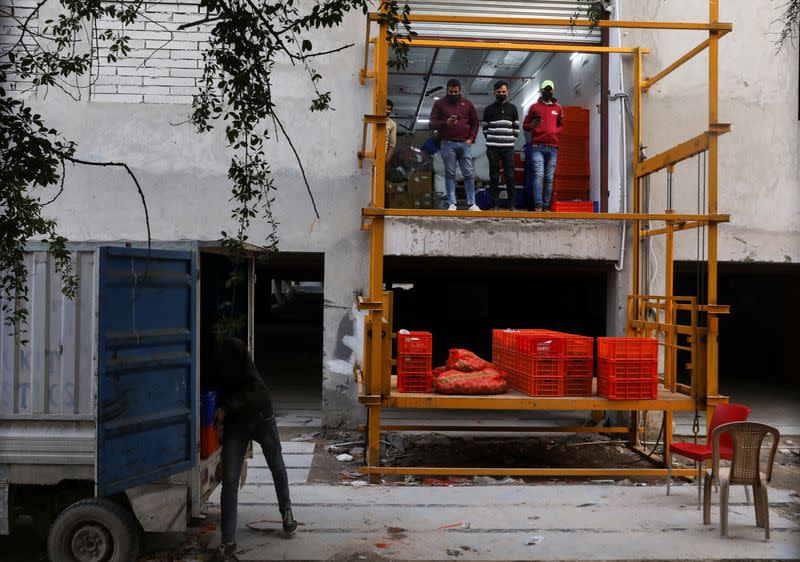 A man unloads groceries from a vehicle at a dark store of the SoftBank-funded Blinkit in New Delhi